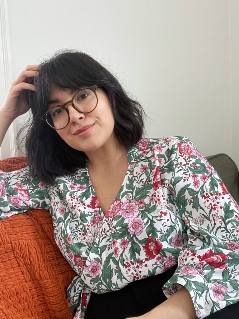 Woman with dark hair in a floral shirt sitting on a green couch.