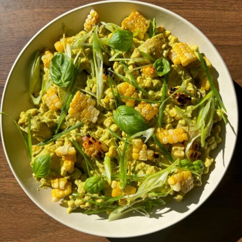 Serving plate of potato salad on a wooden backdrop.