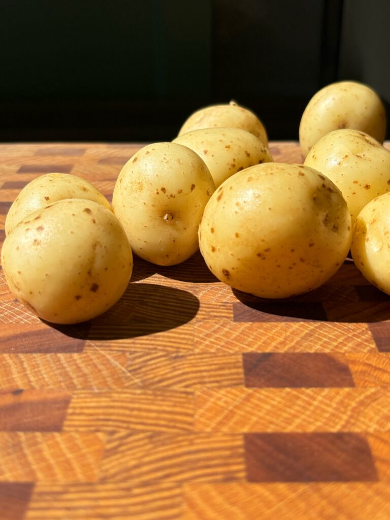 Nine small new potatoes on a wooden cutting board.