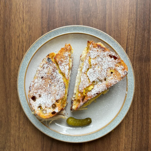 Turkey and Cherry Monte Cristo on a grey plate with a blue rim sitting on a wooden table.