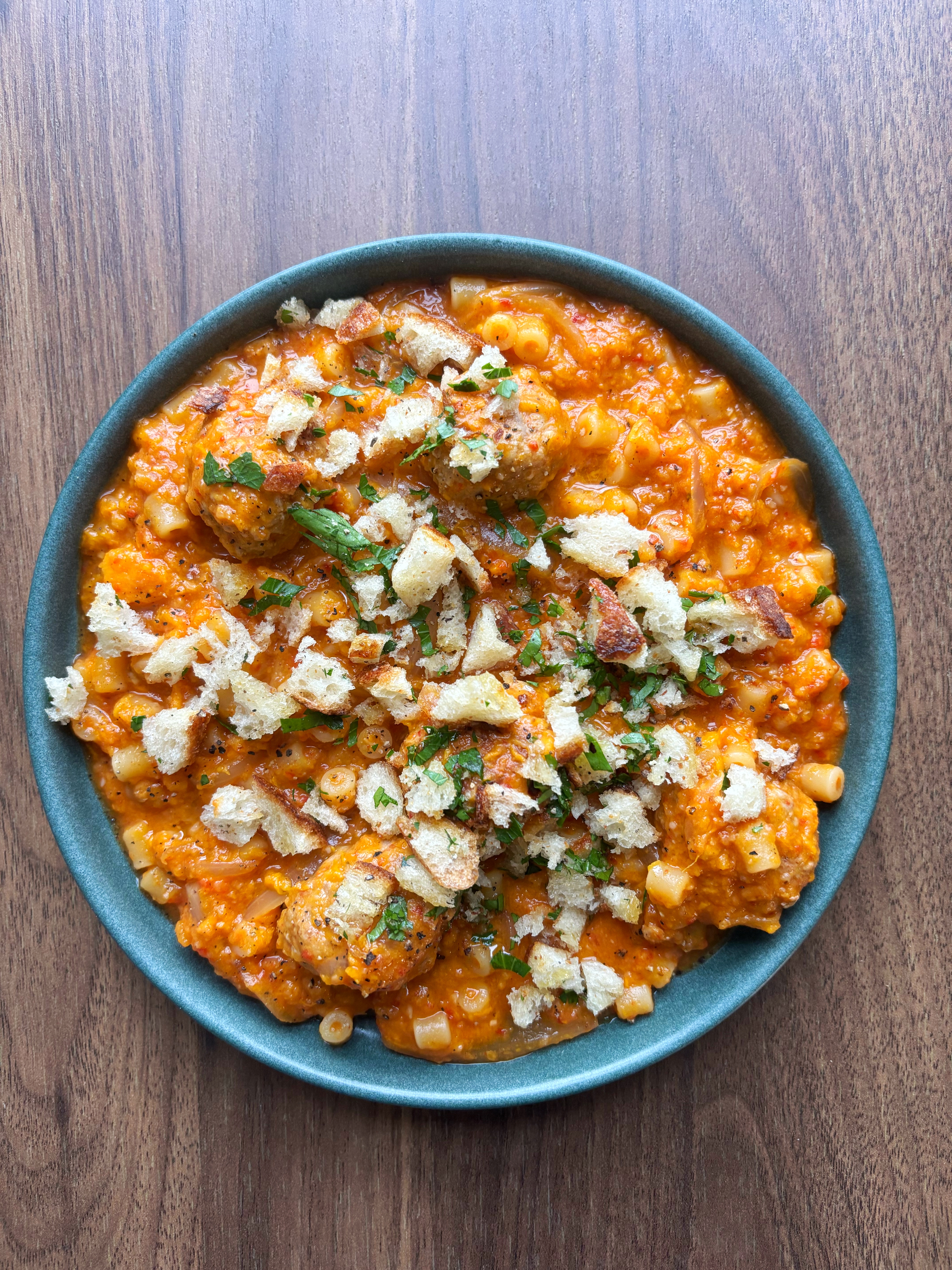 Sweet Potato Romesco with White Beans and Ditali in a green plate on a wooden table.